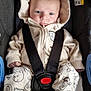 baby, car_seat, cartoon_print, child, clothing, comfort, cute, expression, face, footwear, hoodie, indoors, infant, pajamas, person, resting, safety, seat_belt, straps, young_child