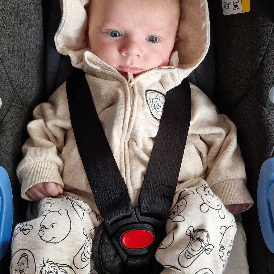 Elizio a rejoint le concours — aidez-le/la à gagner de superbes lots ! baby, car_seat, cartoon_print, child, clothing, comfort, cute, expression, face, footwear, hoodie, indoors, infant, pajamas, person, resting, safety, seat_belt, straps, young_child