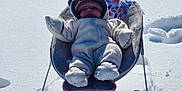 Espyn is registered to the contest to win money with this photo: baby, snow, snowsuit, baby_chair, outdoor, winter, sunlight, shadow, fence, cold, cozy, floral_pattern, child, warm_clothing, footwear, hat, mittens, playful, cute, relaxing