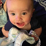 Maverick is registered to the contest to win money with this photo: baby, smiling, face, eyes, blanket, toy, hand, infant, cute, happy, clothing, lying, child, soft, pattern, fabric, closeup, skin, mouth, expression