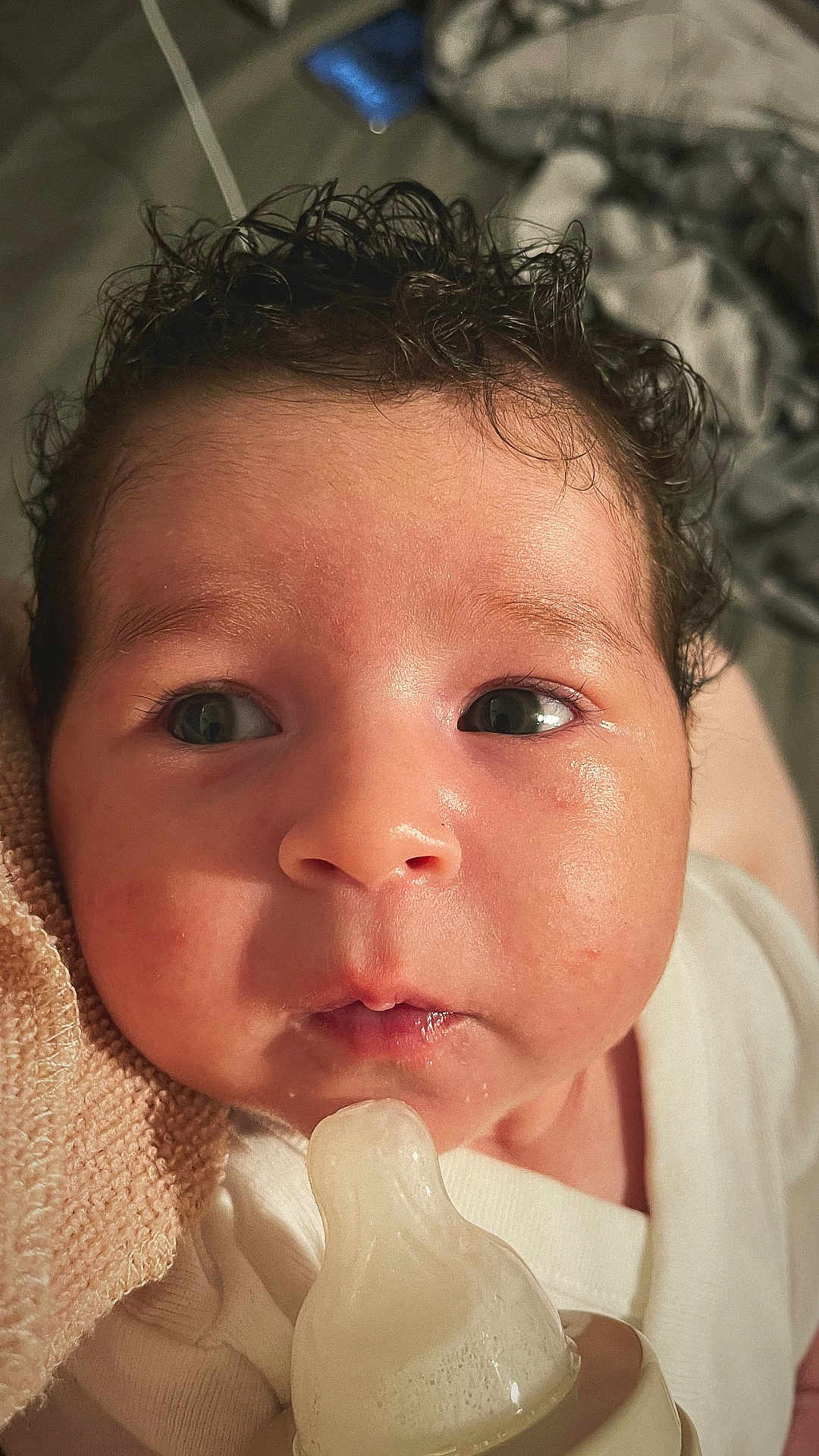Zeynep joined the competition — help win amazing prizes! baby, infant, face, closeup, curly_hair, milk_bottle, nipple, blanket, skin, eyes, mouth, clothing, newborn, cute, expression, indoors, person, soft_lighting, portrait, young_child