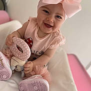Keyla a rejoint le concours — aidez-le/la à gagner de superbes lots ! baby, child, smiling, pink_bow, headband, toy, soft_toy, pink_clothing, sitting, indoor, happy, cute, footwear, shoes, tutu, portrait, face, infant, playful, young_child