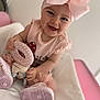 baby, child, smiling, pink_bow, headband, toy, soft_toy, pink_clothing, sitting, indoor, happy, cute, footwear, shoes, tutu, portrait, face, infant, playful, young_child