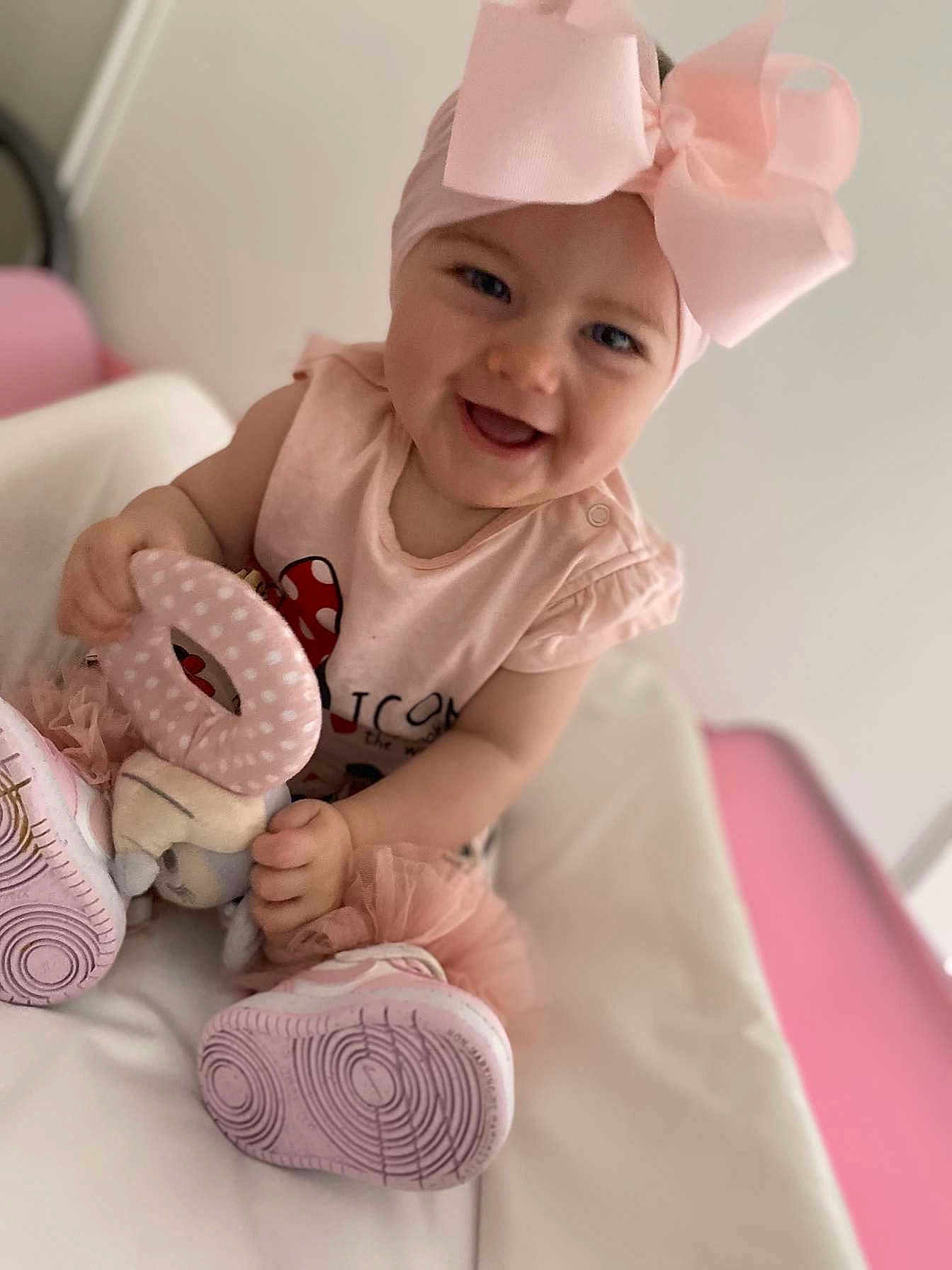 Keyla a rejoint le concours — aidez-le/la à gagner de superbes lots ! baby, child, smiling, pink_bow, headband, toy, soft_toy, pink_clothing, sitting, indoor, happy, cute, footwear, shoes, tutu, portrait, face, infant, playful, young_child