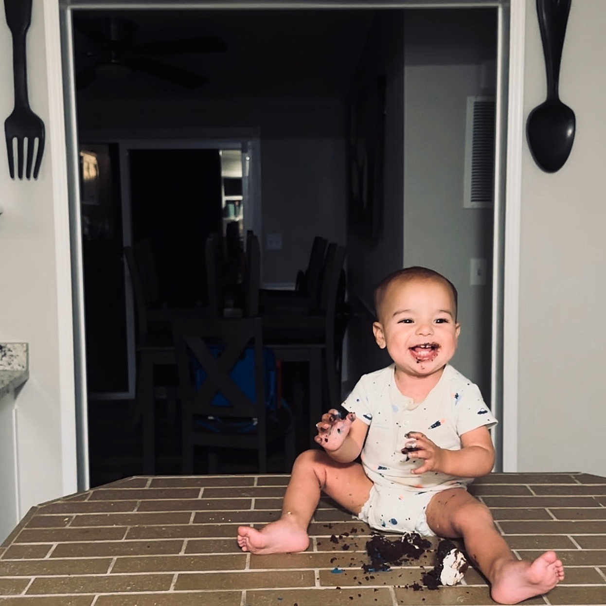 Kamden is registered to the contest to win money with this photo: baby, bodypart, clothing, cream, cutlery, dessert, door, face, finger, food, head, icecream, pants, person, photography, portrait, shorts, sitting, spoon, t_shirt