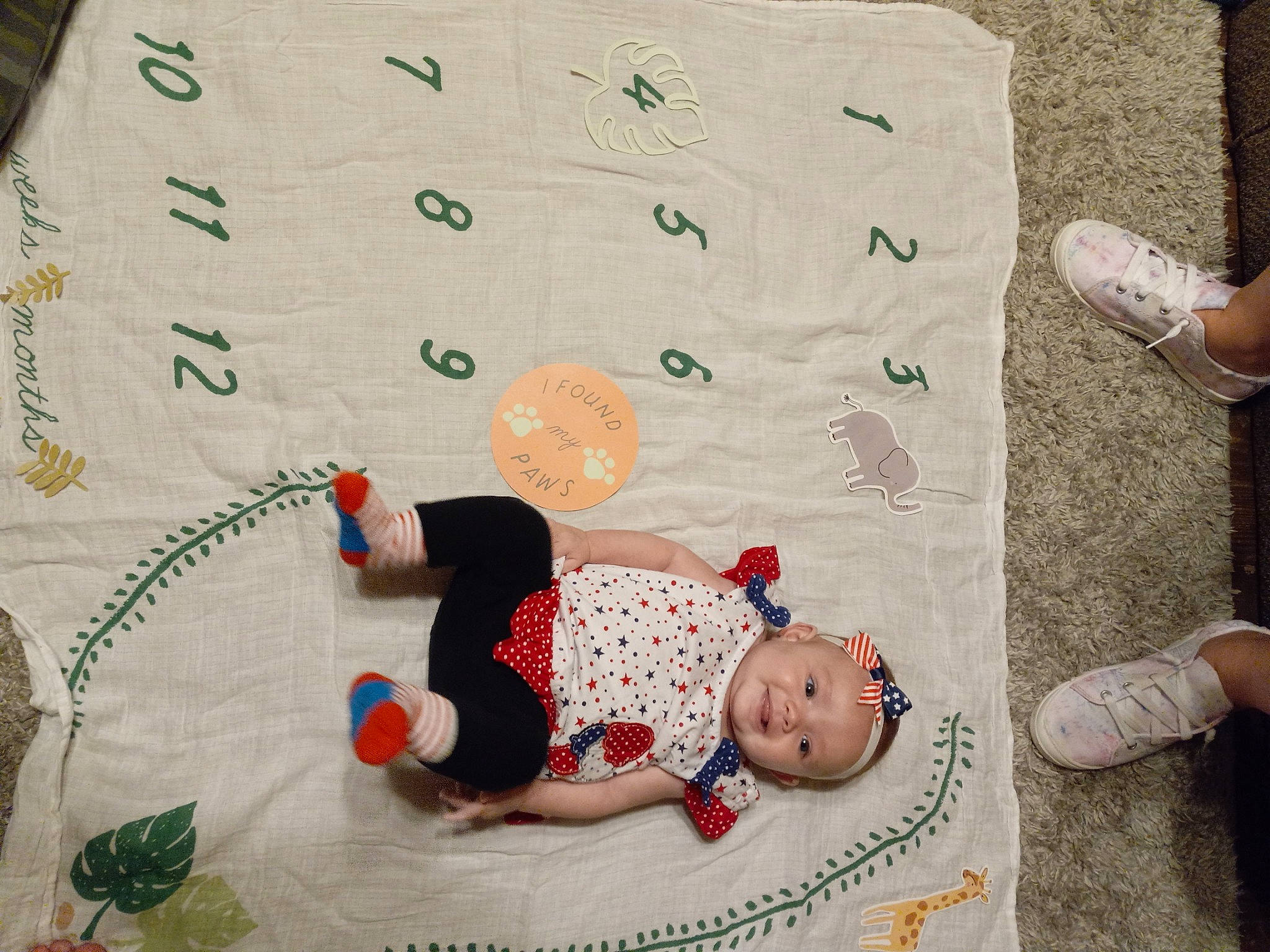 Avalynn is registered to the contest to win money with this photo: baby, baby_toddler_clothing, barefoot, calf, child, comfort, craft, flooring, font, foot, grass, headwear, human_leg, joy, linens, pattern, person, room, sock, t_shirt