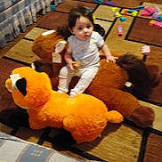 Steven is registered to the contest to win money with this photo: brown, building_blocks, carpet, child, couch, floor, furniture, hair, hand, indoor, kid, living_room, orange, person, playtime, plush, seat, stuffed_animal, toy, white_clothing