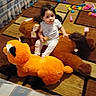 brown, building_blocks, carpet, child, couch, floor, furniture, hair, hand, indoor, kid, living_room, orange, person, playtime, plush, seat, stuffed_animal, toy, white_clothing