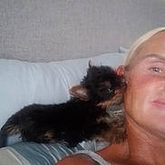 Theo is registered to the contest to win money with this photo: person, dog, puppy, bed, pillow, headboard, smile, resting, nuzzle, indoor, blond_hair, tank_top, closeup, pet, animal, friendship, companion, cute, fur, face