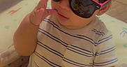 Fernando joined the competition — help win amazing prizes! baby, casual, child, comfortable, cute, funny, glasses, hand, indoor, infant, person, playpen, portrait, reflection, short_hair, sitting, striped_shirt, sunglasses, toddler, toy