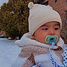 Fernando is registered to the contest to win money with this photo: accessory, baby, blanket, brick_wall, building, bundle, child, cold_weather, cute, face, infant, knit_hat, outdoor, pacifier, portrait, scarf, snow, tree, warm, winter_clothing
