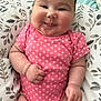 Lena-Sage joined the competition — help win amazing prizes! baby, infant, smiling, pink_onesie, cute, chubby_cheeks, tongue_out, pillow, floral_pattern, cushion, lying_down, indoors, happy, person, child, skin, face, hand, clothing, expression