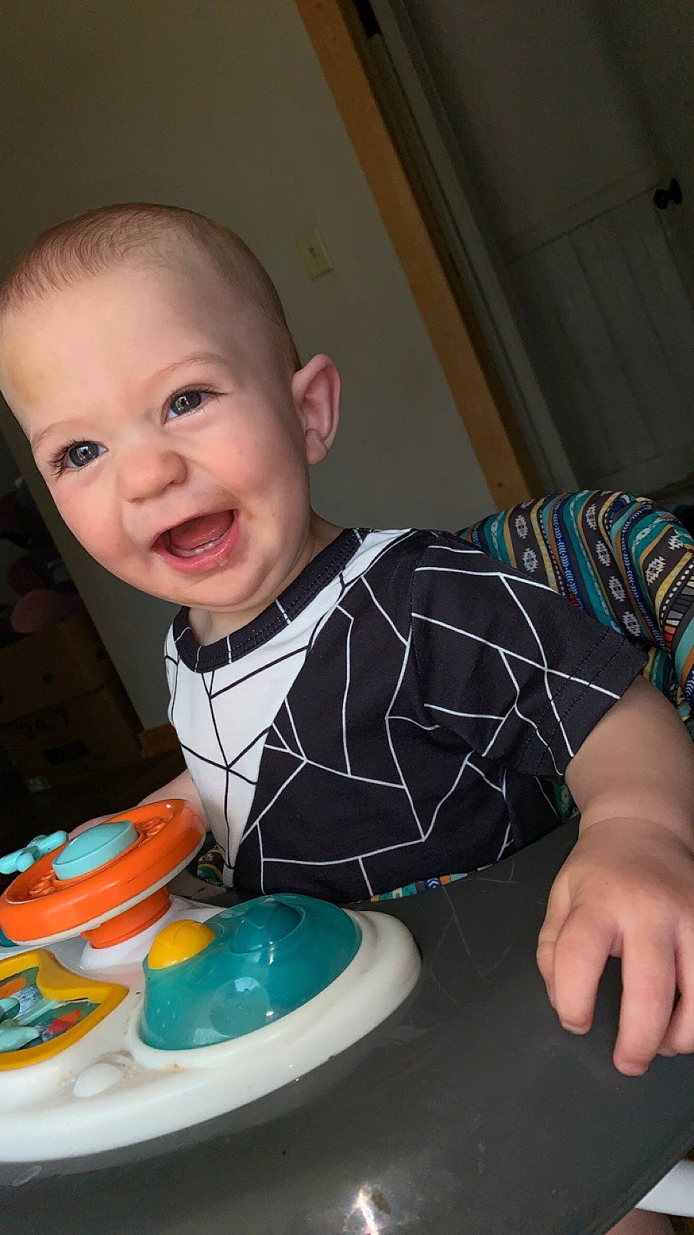 Treyson is registered to the contest to win money with this photo: baby, baby_toddler_clothing, cheek, child, dishware, drinkware, finger, fun, happy, iris, joy, person, plate, product, serveware, sitting, sleeve, smile, t_shirt, table
