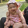baby, child, smiling, pink_hat, pink_clothing, outdoor, nature, greenery, person, happy, infant, sunlight, park, grass, trees, bench, holding, cute, summer, portrait