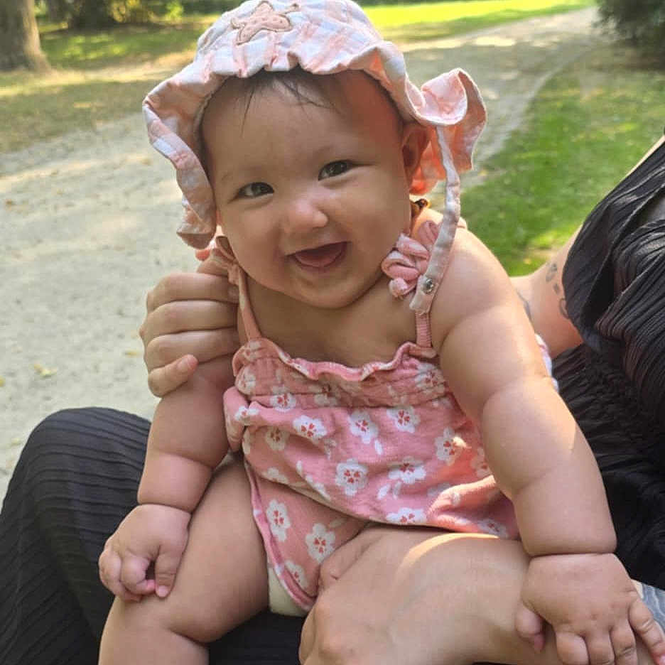 Mai Linh participe au concours pour gagner de l'argent avec cette photo : baby, bench, child, cute, grass, greenery, happy, holding, infant, nature, outdoor, park, person, pink_clothing, pink_hat, portrait, smiling, summer, sunlight, trees