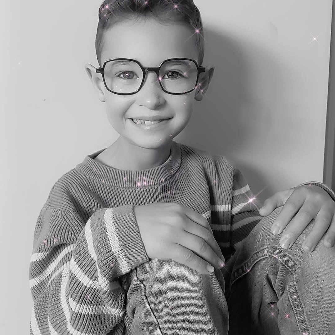 Aedhan Herrbach participe au concours pour gagner de l'argent avec cette photo : black_and_white, boy, casual_clothing, child, eyewear, face, floor, glasses, hands, happy, indoor, jeans, portrait, short_hair, sitting, smiling, sparkle_effect, striped_sweater, sweater, young