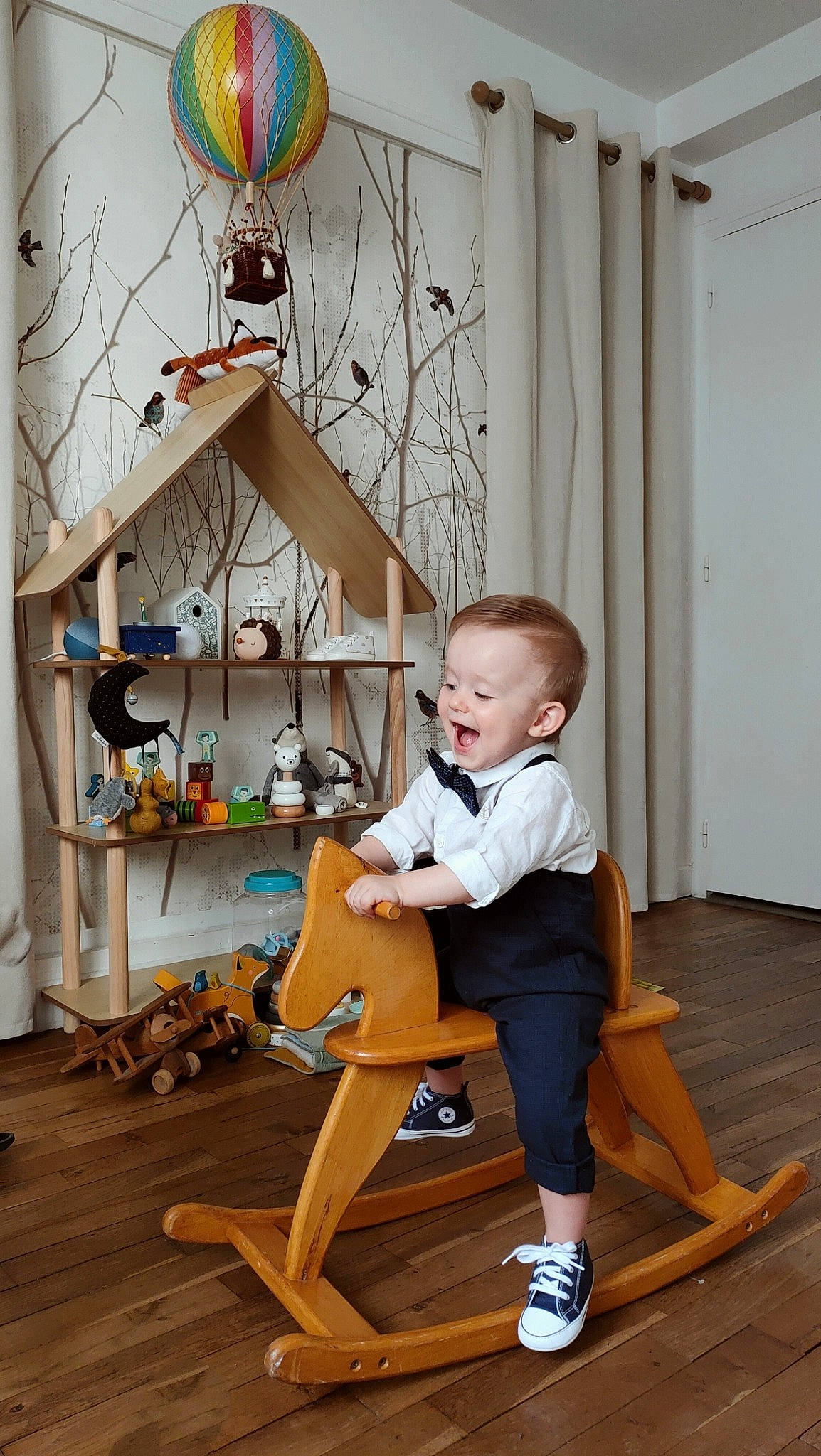 Pierre participe au concours pour gagner de l'argent avec cette photo : art, baby, baby_toddler_clothing, balloon, child, flooring, hardwood, knee, laminate_flooring, leisure, person, room, shelf, shorts, sitting, toddler, toy, tree, white, wood