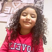 Raissa a rejoint le concours — aidez-le/la à gagner de superbes lots ! casual_clothing, child, cozy, curly_hair, decor, face, flowers, girl, happy, home, indoor, person, pink_sweatshirt, portrait, relaxed, selfie, sitting, smiling, wall_art, young