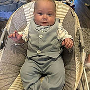 Roland is registered to the contest to win money with this photo: baby, child, infant, vest, pants, baby_seat, toy, buzz_lightyear, floor, wooden_floor, carpet, cushion, indoor, person, clothing, cute, smile, hand, face, home