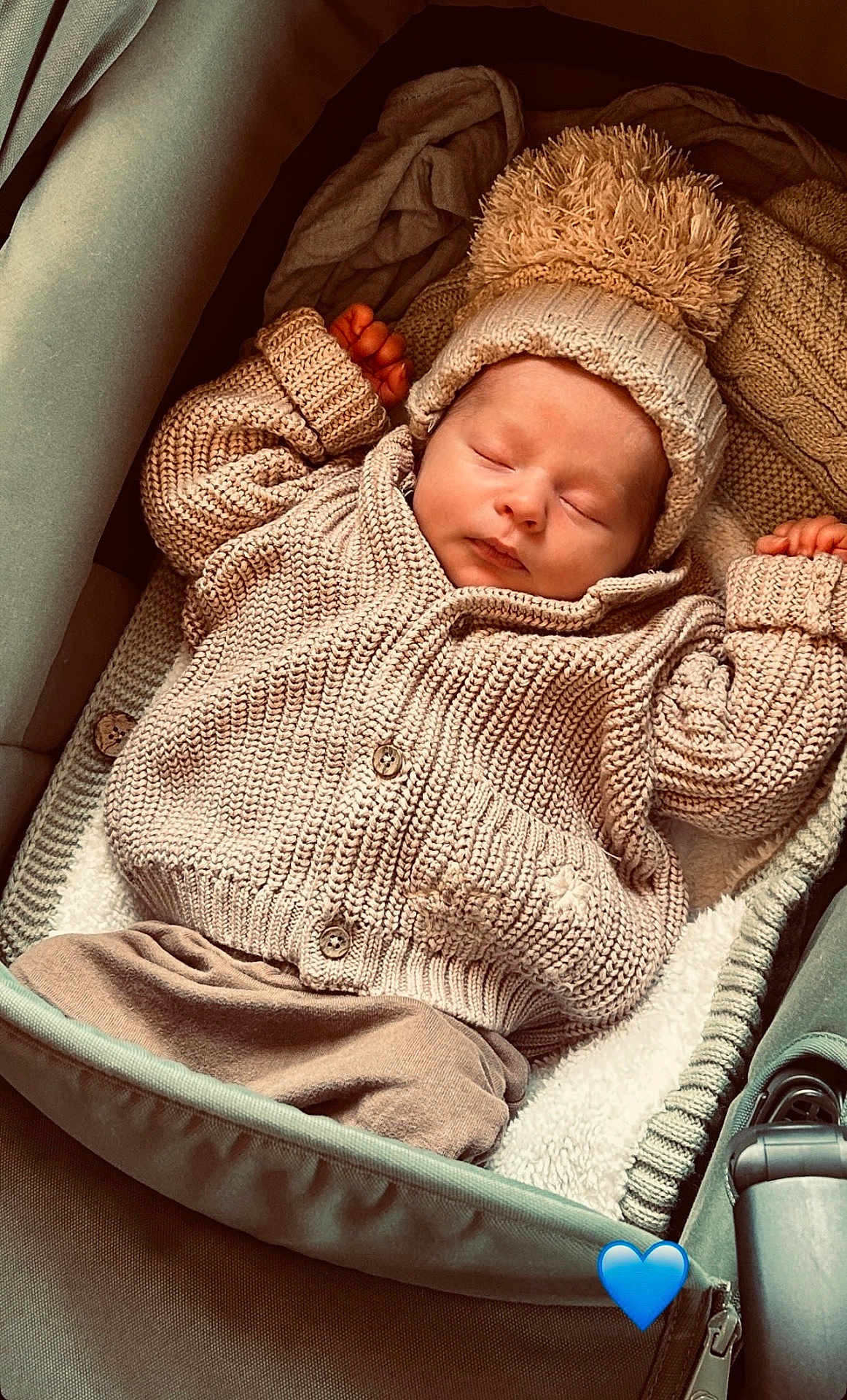 Luca is registered to the contest to win money with this photo: baby, sleeping, knitted_sweater, pom_pom_hat, cozy, infant, carrier, blanket, soft, peaceful, cute, child, warm_clothing, resting, indoor, portrait, newborn, adorable, headwear, babywearing