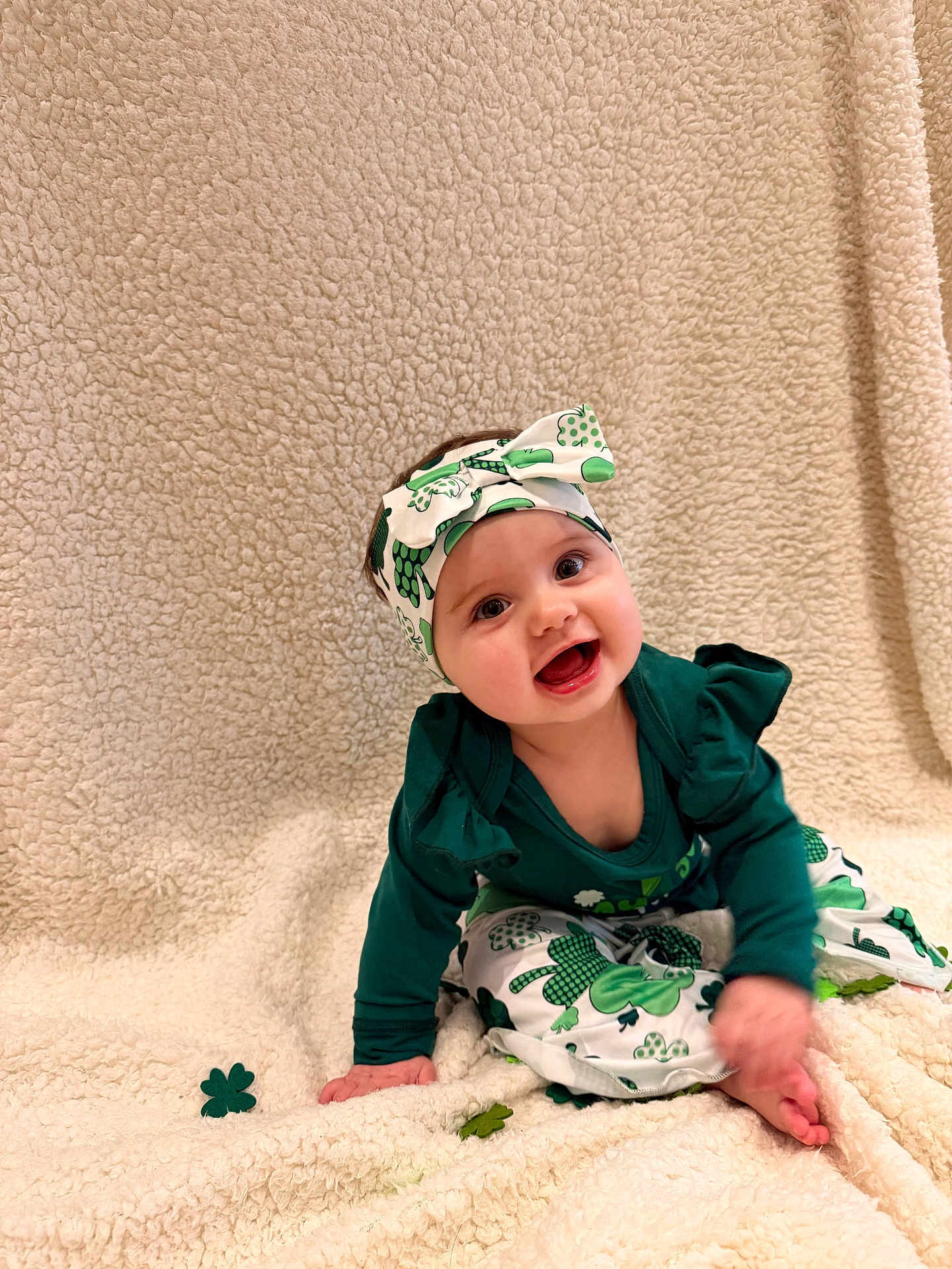 Ambre a rejoint le concours — aidez-le/la à gagner de superbes lots ! baby, blanket, child, festive, green_outfit, happy, headband, headwear, indoor, infant, one_face, open_mouth, patterned_pants, plush_blanket, portrait, shamrock, sitting, smiling, textured_background, toes