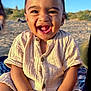 toddler, child, smiling, happy, outdoor, beach, sand, sunlight, buttoned_shirt, sitting, blanket, portrait, face, young_child, cute, natural_light, casual_clothing, daytime, skin, baby