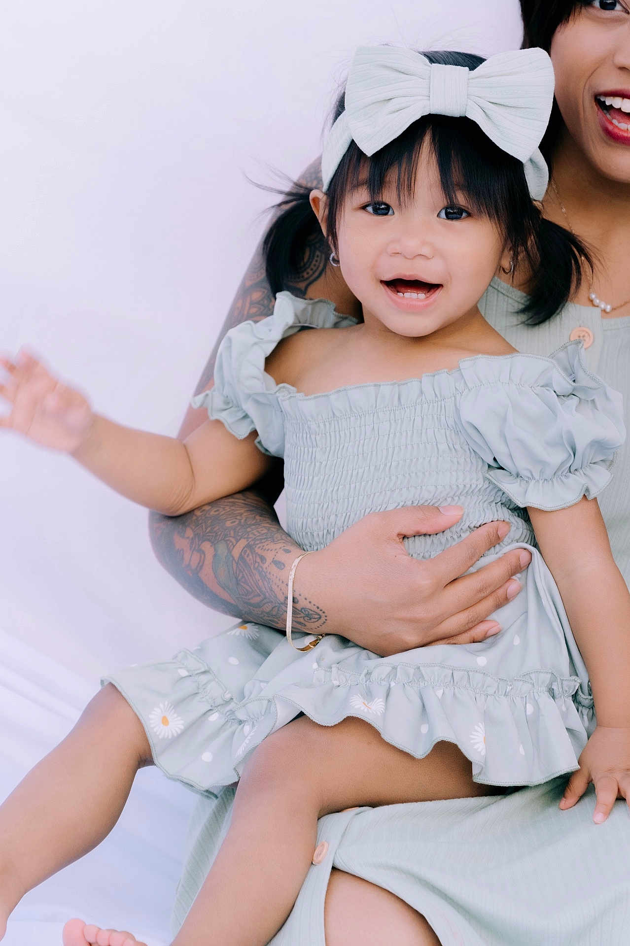 Jade is registered to the contest to win money with this photo: toddler, child, smiling, bow, dress, tattoo, arm, adult, happy, sitting, holding, cute, portrait, indoor, person, fashion, skin, hand, face, joyful