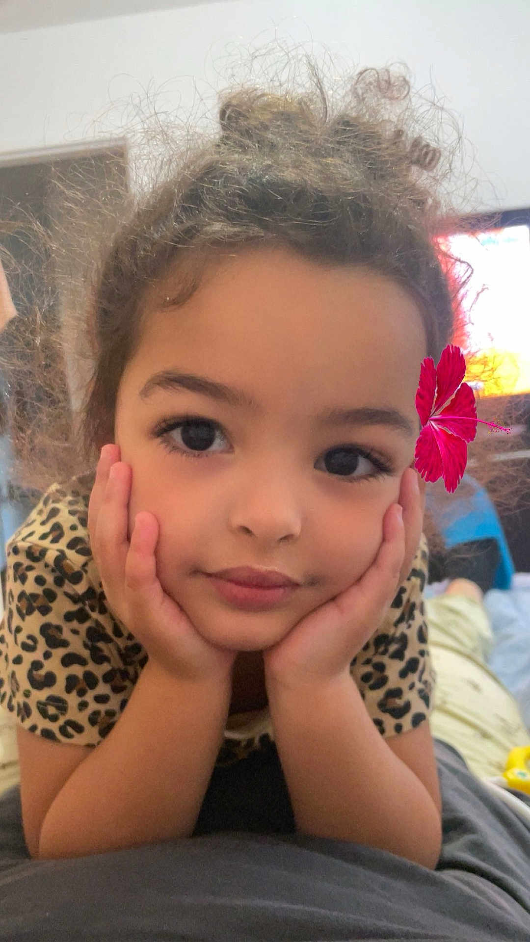 Naelle participe au concours pour gagner de l'argent avec cette photo : child, face, hands, flower, curly_hair, indoor, leopard_print, shirt, smile, portrait, close_up, young_girl, cute, resting, eyes, skin, casual, relaxed, person, home
