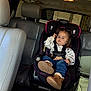 toddler, child, car_seat, vehicle_interior, seatbelt, boots, jeans, long_sleeve_shirt, hair_tied, serious_expression, leather_seats, window, car_headrest, cosco_brand, seat, safety_harness, indoor, person, baby, child_safety