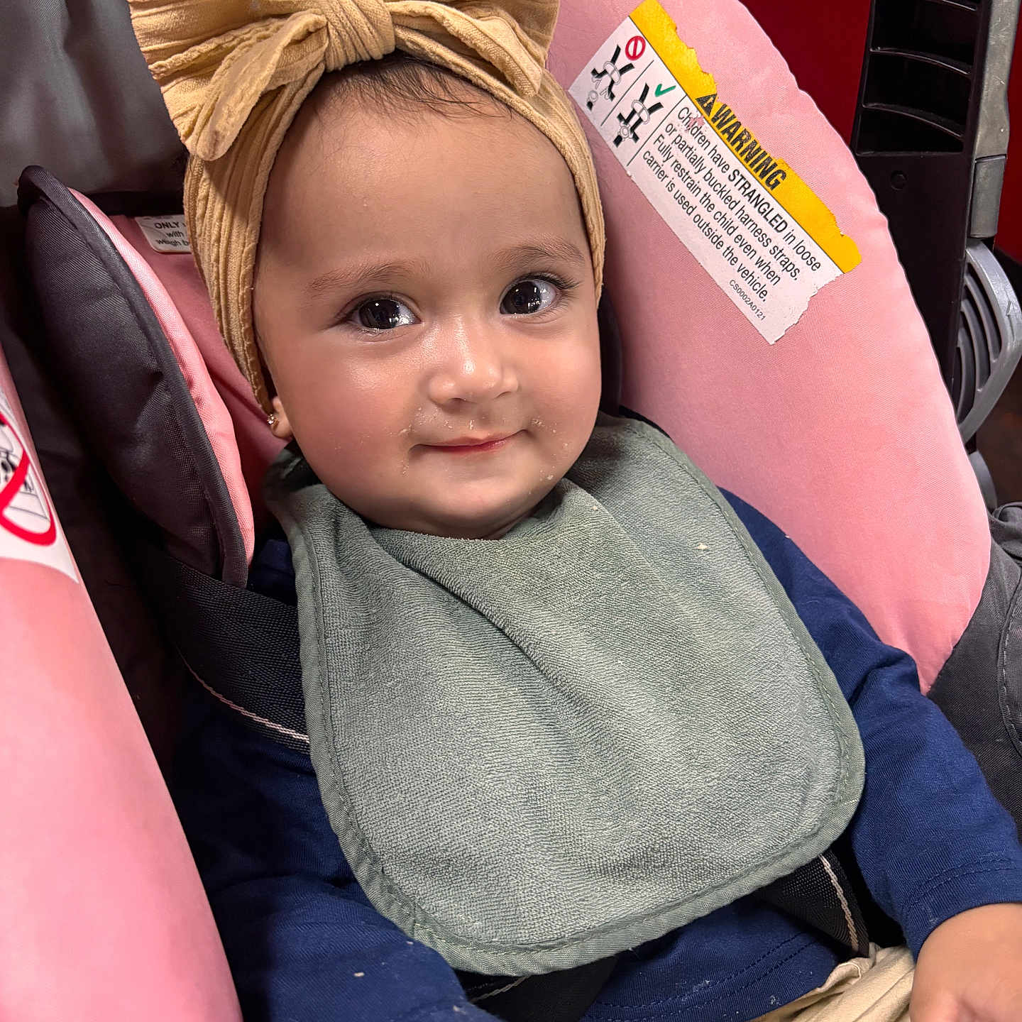 Regina joined the competition — help win amazing prizes! baby, child, infant, smiling, portrait, stroller, car_seat, bow, headband, bib, clothing, sitting, indoors, close_up, face, eyes, happy, adorable, safety_label, vehicle_seat
