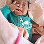baby, infant, smiling, blanket, pink, teal_clothing, unicorn_print, hand, face, cute, cozy, wrapped, happy, child, newborn, soft, sleeping_area, comfort, indoors, portrait