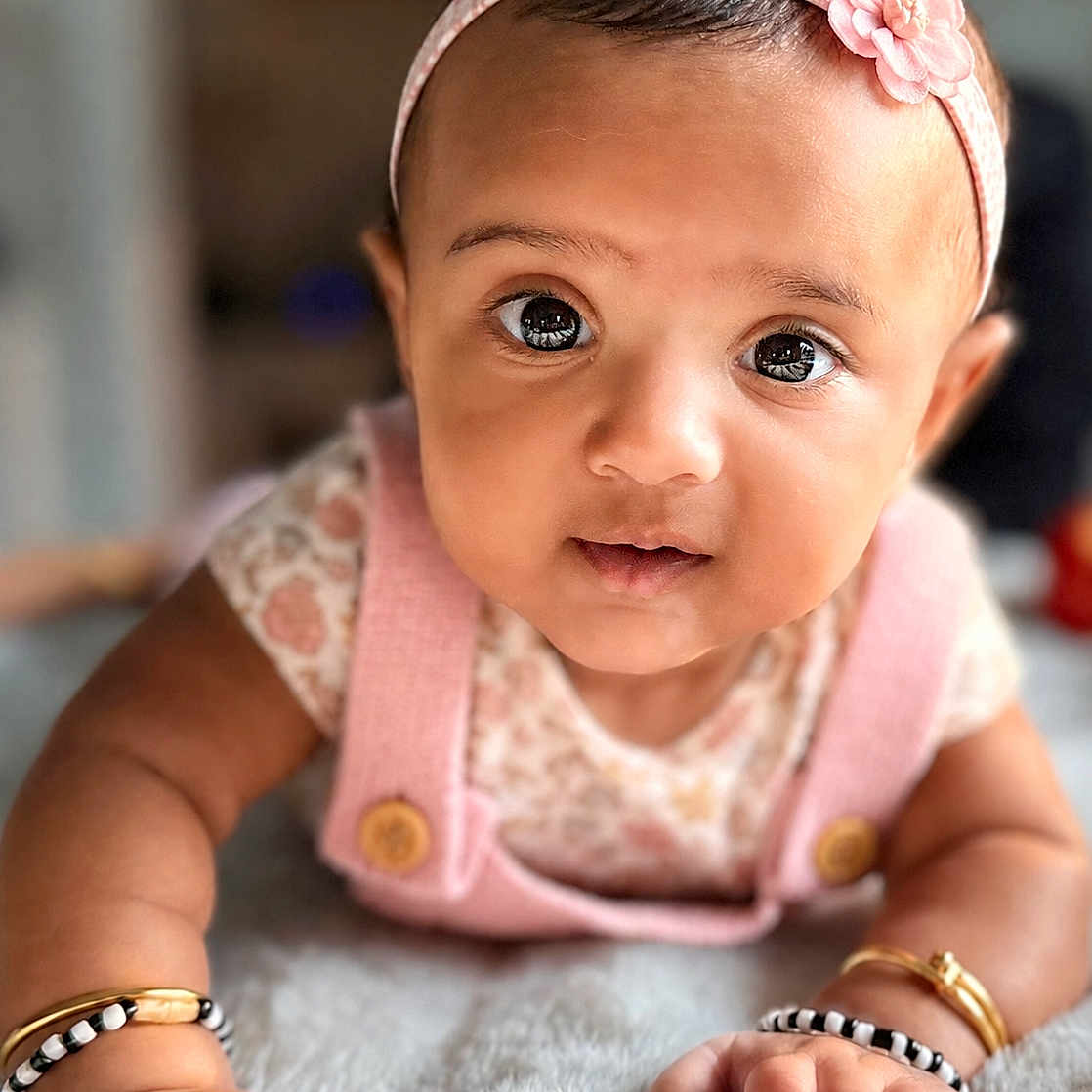 Aryahi is registered to the contest to win money with this photo: adorable, baby, blanket, bracelet, child, closeup, clothing, cute, expression, face, hands, headband, indoor, infant, person, pink, portrait, skin, soft, young
