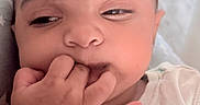 Aryahi is registered to the contest to win money with this photo: baby, bracelet, child, closeup, clothing, cute, expression, face, fingers, hand, head, indoors, infant, person, portrait, sitting, skin, sleepy, white_shirt, young_child