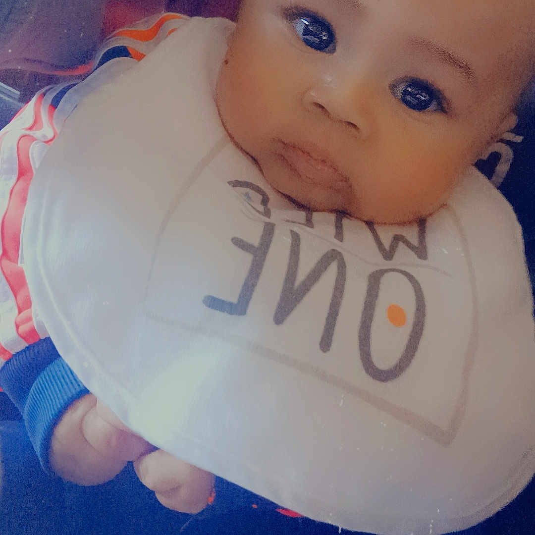 Josiah joined the competition — help win amazing prizes! baby, bib, bodypart, cushion, face, finger, frown, hand, head, homedecor, newborn, person, photography, portrait, sad
