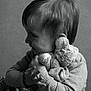 affection, black_and_white, child, cozy, cute, face, hair, hand, happy, hugging, indoor, person, portrait, smile, soft_lighting, sweater, teddy_bear, toy, warm, young