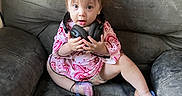 Everleigh is registered to the contest to win money with this photo: toddler, child, headphones, couch, pink_clothing, sitting, curious_expression, indoor, sparkly_shoes, baby, furniture, person, young_child, cute, casual, home, small_child, hands, face, seated