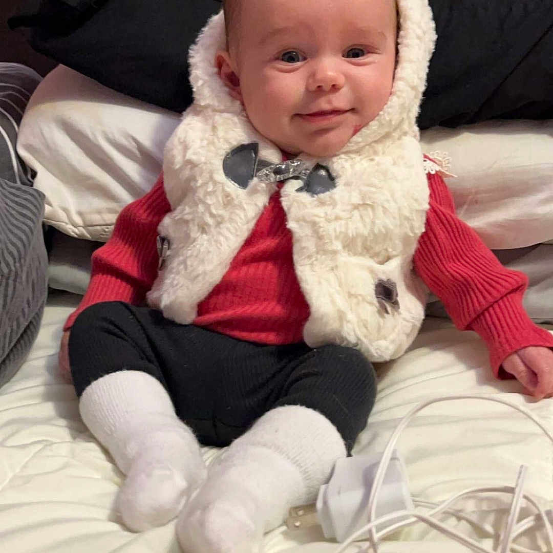 Rosalynn is registered to the contest to win money with this photo: baby, clothing, coat, couch, cushion, face, furniture, hat, head, homedecor, hosiery, jacket, knitwear, person, photography, portrait, sitting, smokepipe, sock, sweater