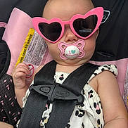 Olivia joined the competition — help win amazing prizes! baby, child, pacifier, sunglasses, heart_shaped, car_seat, safety_harness, pink, cute, infant, clothing, black_straps, white_outfit, patterned, face, portrait, seat, restraint, accessory, young
