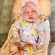 Romèe is registered to the contest to win money with this photo: baby, sleeping, floral_outfit, headband, bow, pink, socks, tattoo, legs, blanket, cozy, infant, newborn, cute, child, apparel, resting, soft, patterned_clothing, indoors