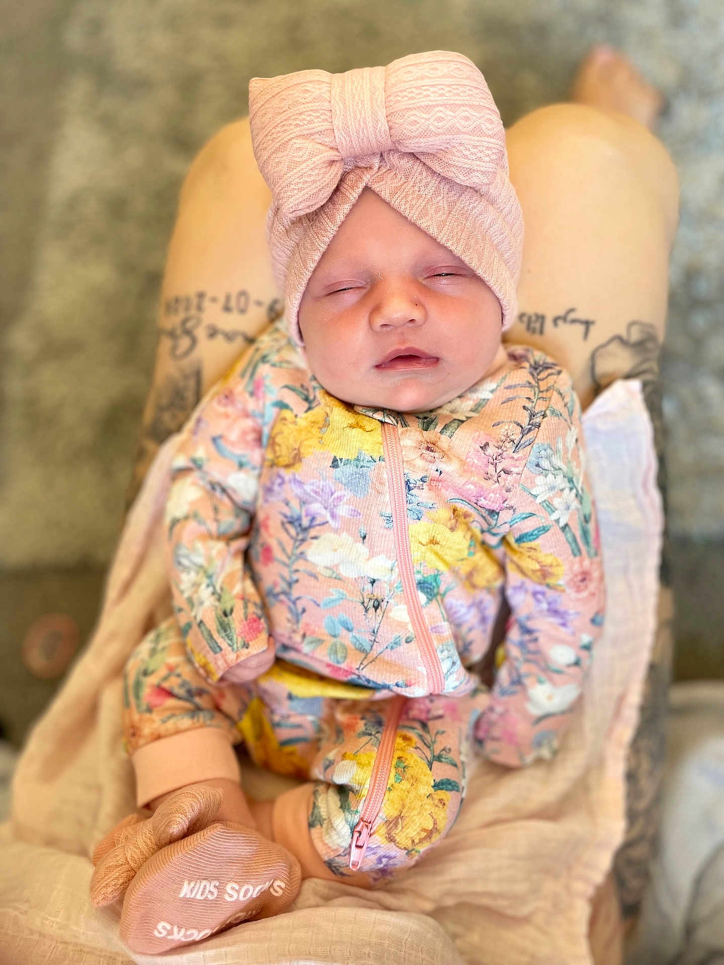 Romèe is registered to the contest to win money with this photo: baby, sleeping, floral_outfit, headband, bow, pink, socks, tattoo, legs, blanket, cozy, infant, newborn, cute, child, apparel, resting, soft, patterned_clothing, indoors