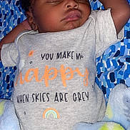 Trelyn is registered to the contest to win money with this photo: baby, sleeping, infant, onesie, blanket, patterned_blanket, cute, peaceful, indoor, soft_lighting, child, young, resting, cozy, smiling_sun, rainbow, text_on_clothing, closeup, portrait, relaxed