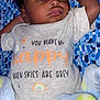 baby, sleeping, infant, onesie, blanket, patterned_blanket, cute, peaceful, indoor, soft_lighting, child, young, resting, cozy, smiling_sun, rainbow, text_on_clothing, closeup, portrait, relaxed