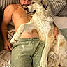 dog, golden_retriever, man, person, shirtless, couch, blanket, pillow, indoor, sleeping, cuddling, pet, large_dog, white_fur, relaxed, portrait, funny, cozy, living_room, human_animal_bond
