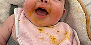 Mya participe au concours pour gagner de l'argent avec cette photo : baby, bib, cheeks, child, closeup, clothing, cushion, cute, feeding, food_stains, happy, indoor, infant, messy_face, mouth_open, person, pink_bib, seat, skin, smiling