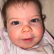 Mya a rejoint le concours — aidez-le/la à gagner de superbes lots ! baby, face, closeup, eyes, rosy_cheeks, bib, infant, child, smile, cute, soft_texture, skin, portrait, young, expression, indoors, head, hair, person, curly_hair