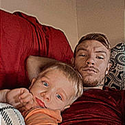 Cambridge joined the competition — help win amazing prizes! child, adult, couch, blanket, pillow, indoor, relaxing, selfie, casual, comfort, person, face, blue_eyes, short_hair, red_shirt, orange_shirt, expression, home, resting, family