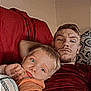 child, adult, couch, blanket, pillow, indoor, relaxing, selfie, casual, comfort, person, face, blue_eyes, short_hair, red_shirt, orange_shirt, expression, home, resting, family