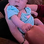 baby, infant, child, hand, arm, onesie, person, indoor, holding, tattoo, bracelet, curious, expression, skin, face, fist, reaching, couch, clothing, human