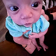 Kenzley is registered to the contest to win money with this photo: baby, infant, close_up, face, large_eyes, blue_clothing, person, hand, arm, skin, feet, indoor, couch, holding, portrait, child, young, human, expression, looking