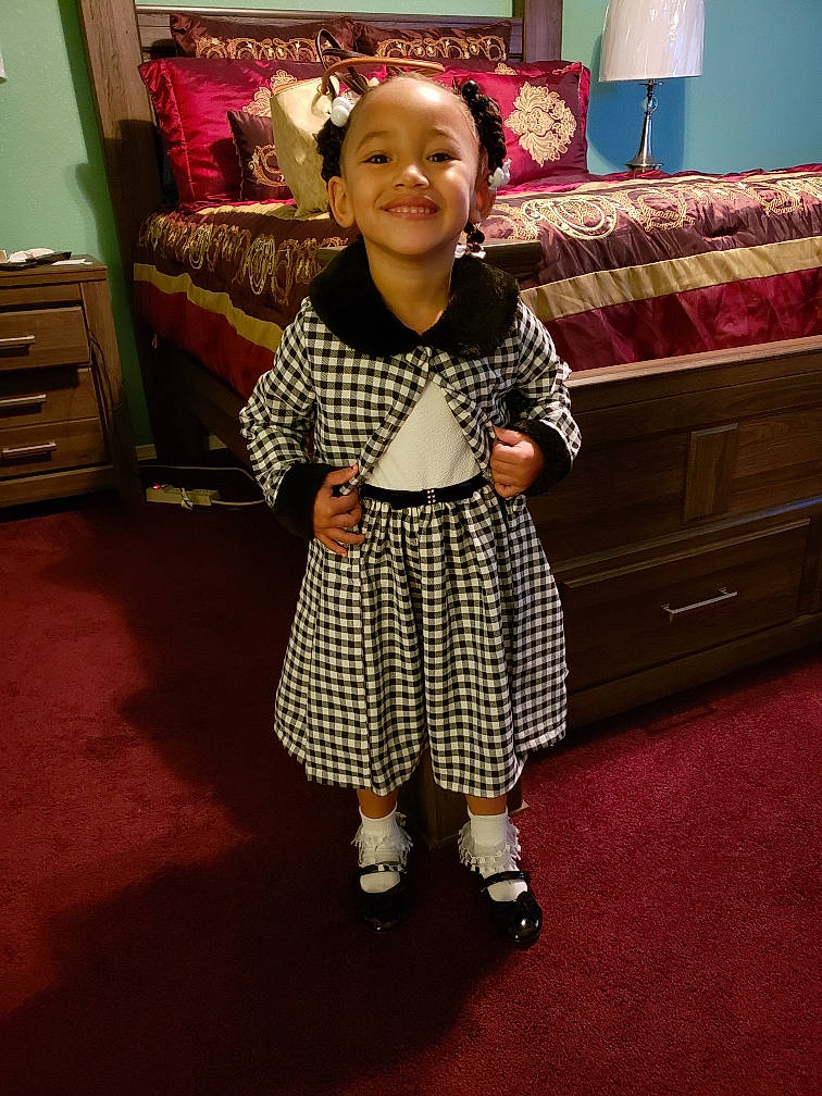 A'Myah is registered to the contest to win money with this photo: child, clothing, costume, day, design, dress, flooring, fun, girl, joy, outerwear, pattern, person, plaid, polka_dot, product, skin, smile, snapshot, standing